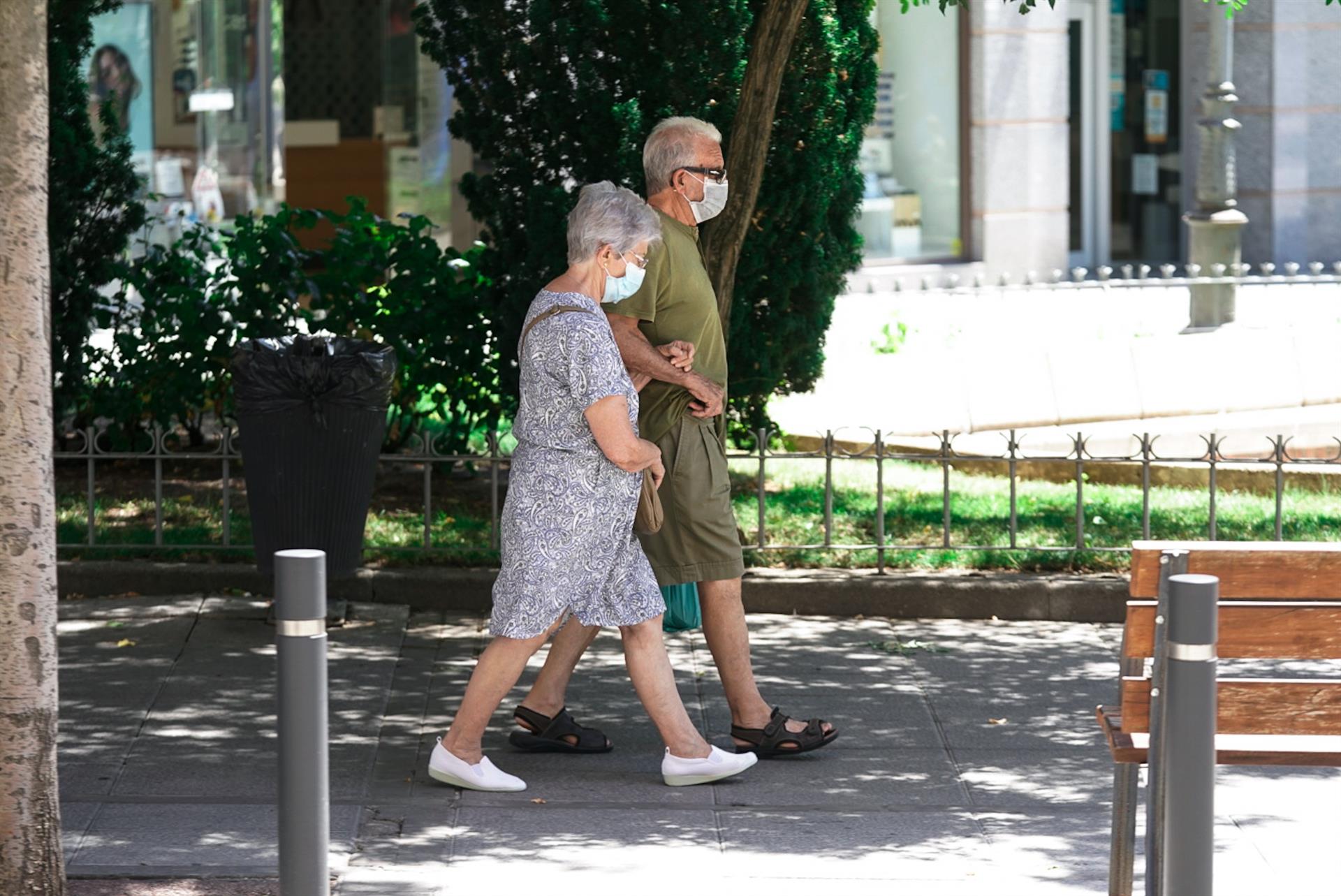 Una pareja de ancianos con mascarilla camina por la calle cogida del brazo