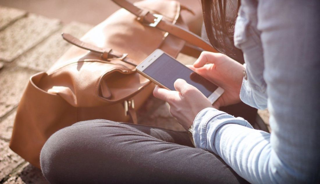 Una persona sentada mirando el teléfono móvil. EP