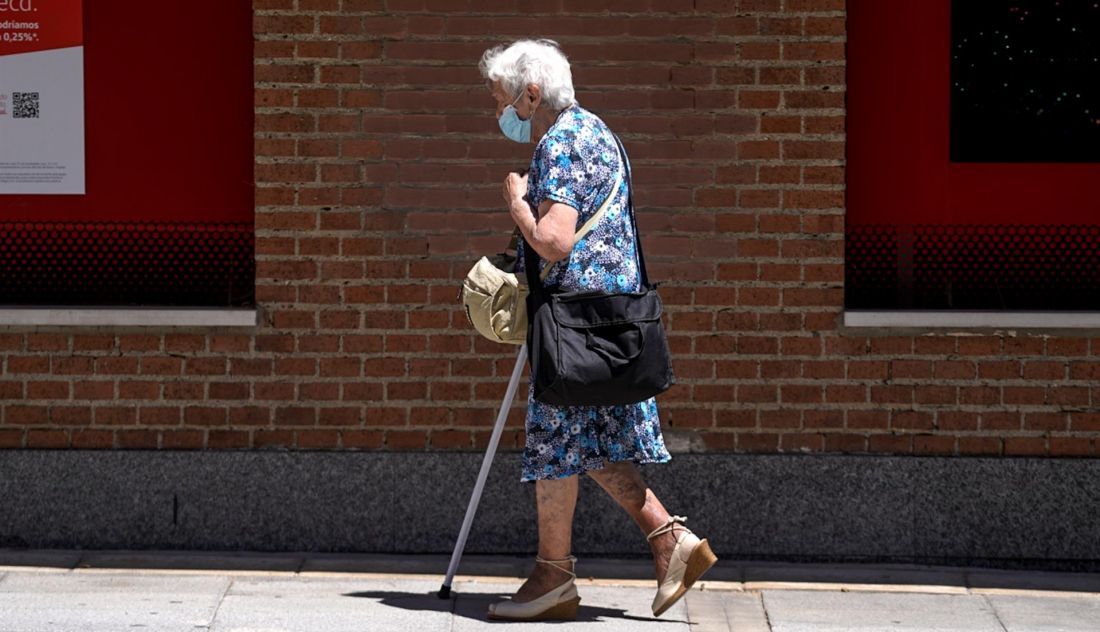 Una anciana con mascarilla camina por la calle ayudada de una muleta | Foto: EP