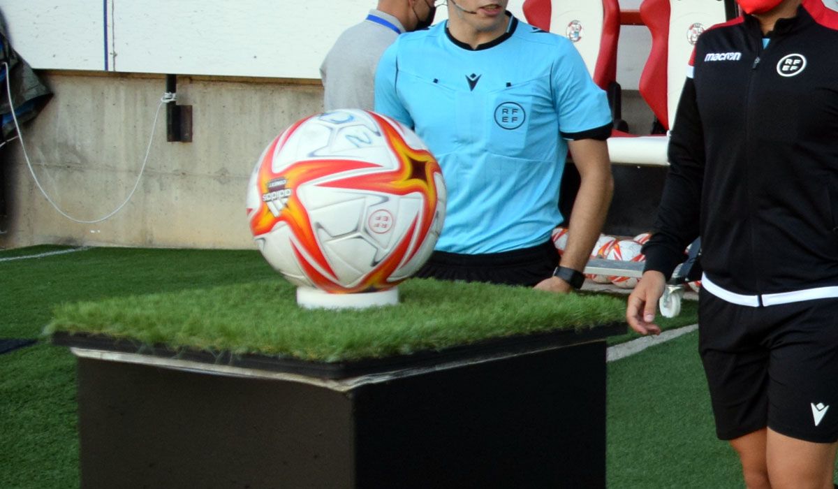 El trío arbitral va a coger el balón de un partido