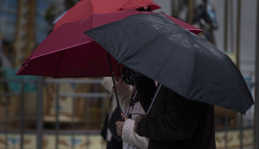 Ciudadanos pasean bajo la lluvia provistos de paraguas