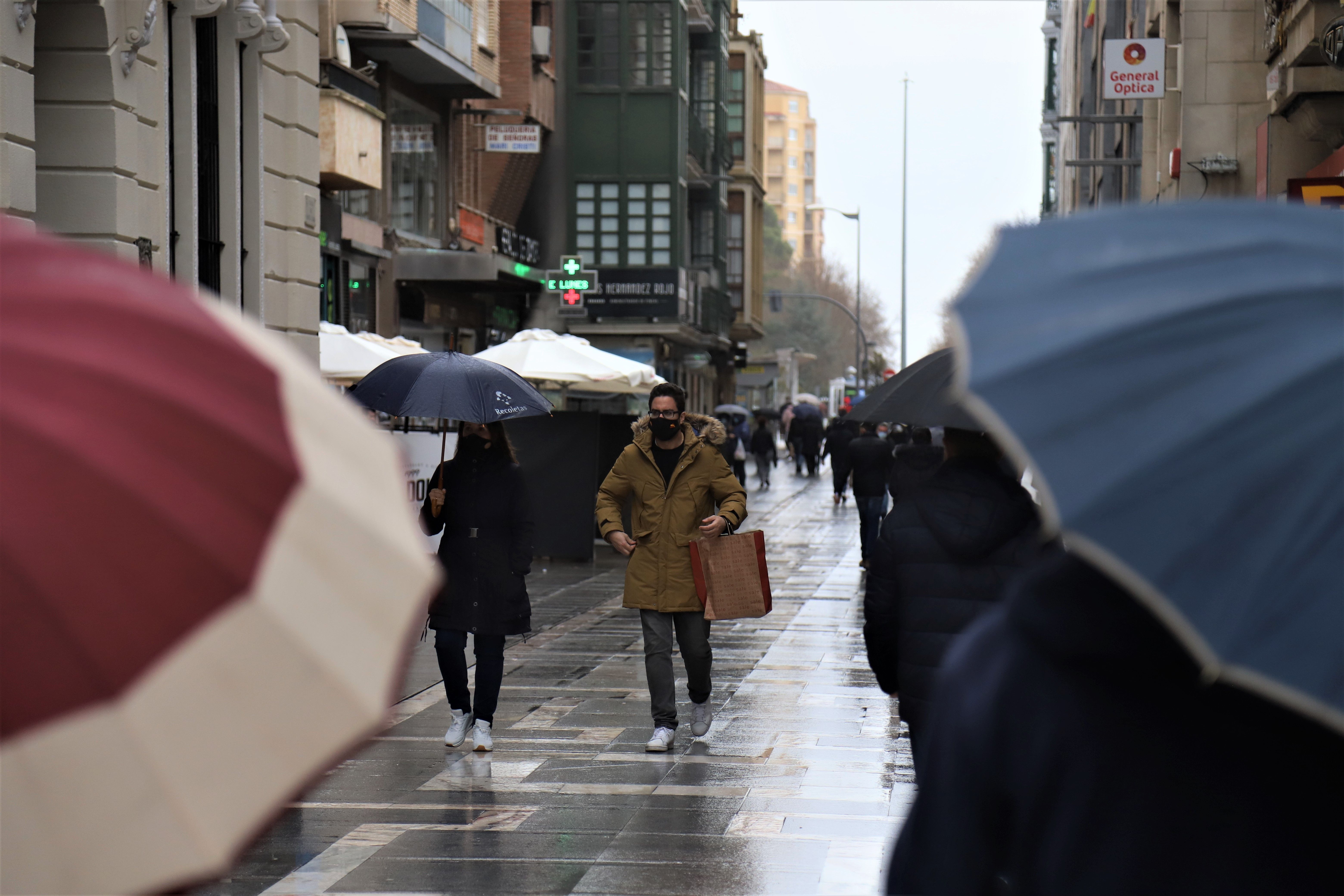 Personas paseando por Santa Clara un día de lluvia