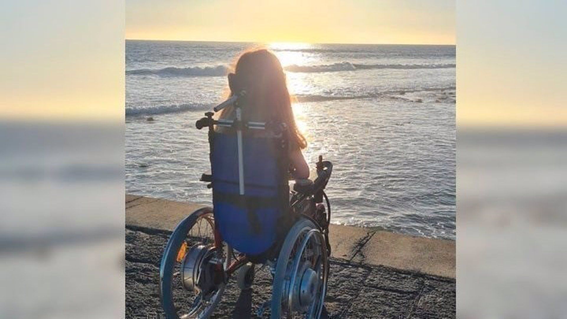 Una joven en silla de ruedas mirando al mar