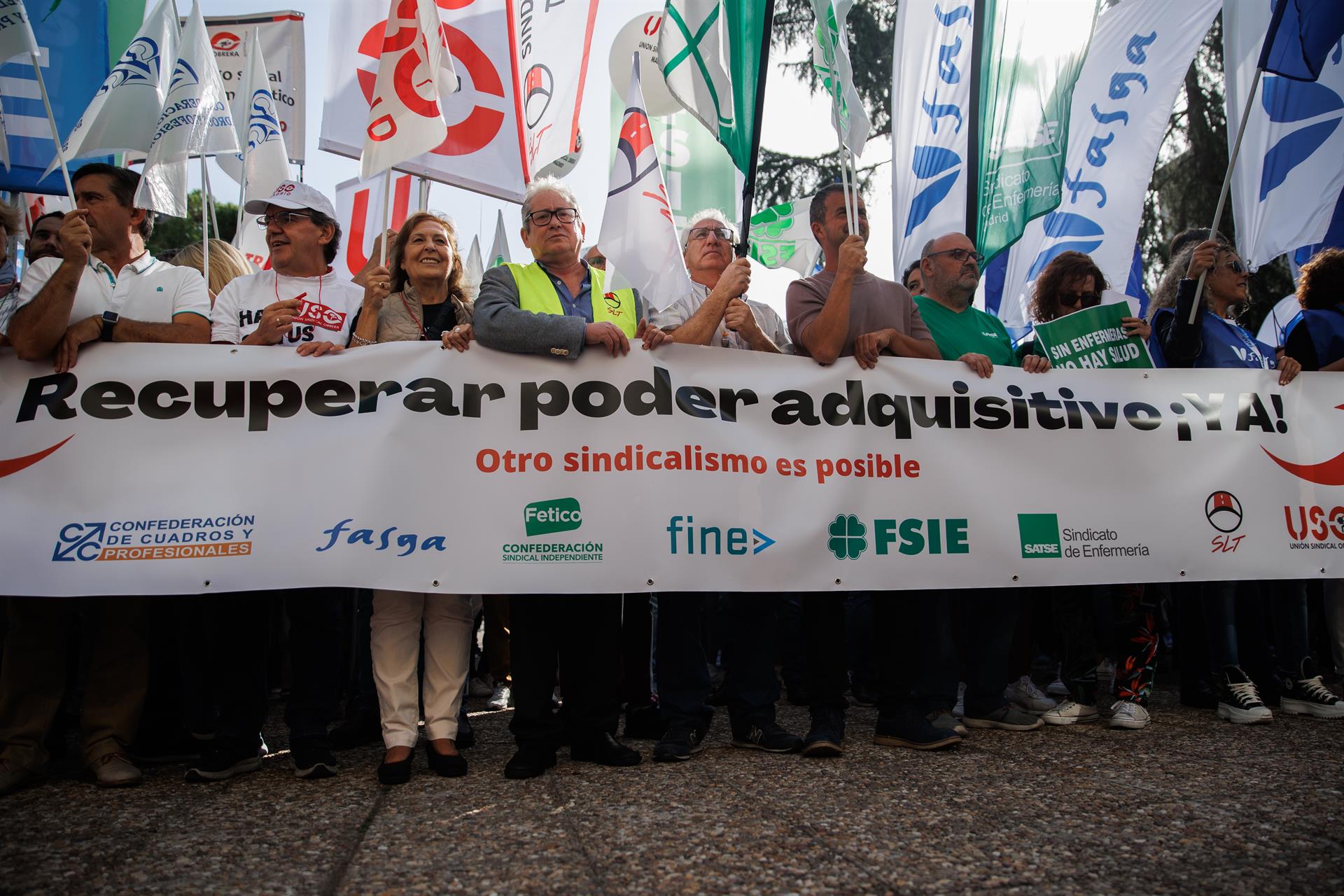 Un grupo de personas pertenecientes a sindicatos de trabajos sostienen banderines y una pancarta durante una concentración ante el Ministerio de Trabajo