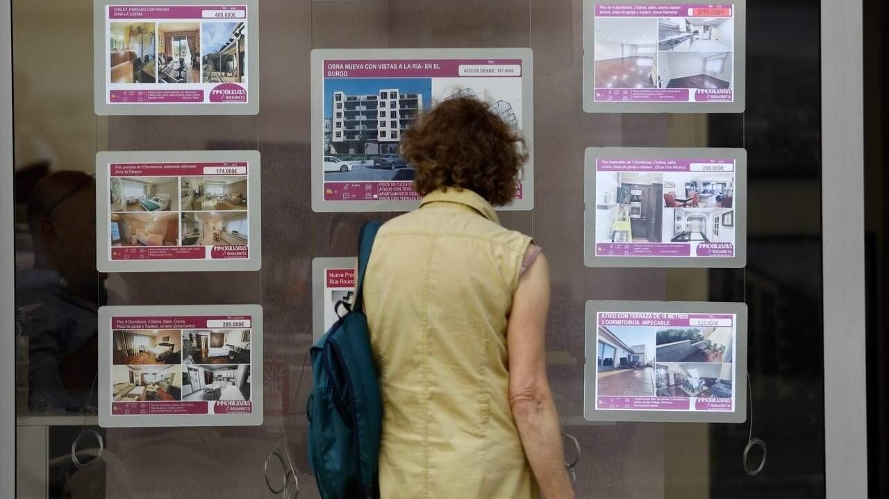 Una mujer mirando un escaparate de una inmobiliaria. EP