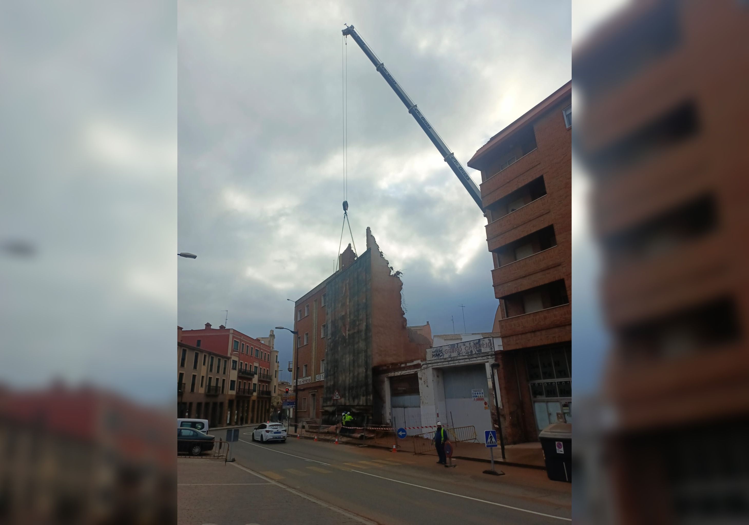 Una enorme grúa para instalar la lona previa al derribo de la fachada del edificio