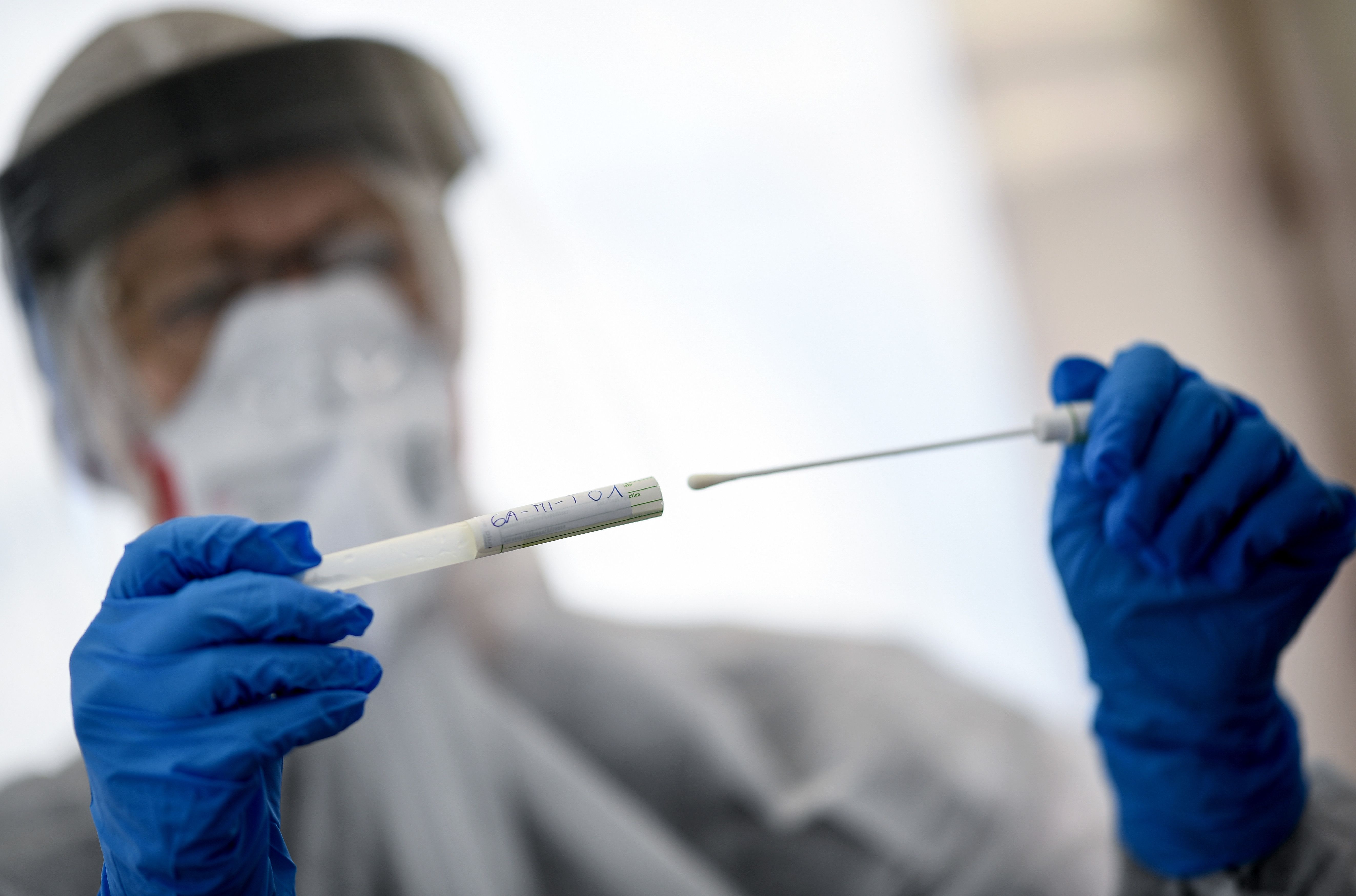  23 April 2020, Berlin: A staff member from the public health department in Mitte holds a swab tool in her hand at a drive-in coronavirus test station on the central fairground, amid the coronavirus ou 