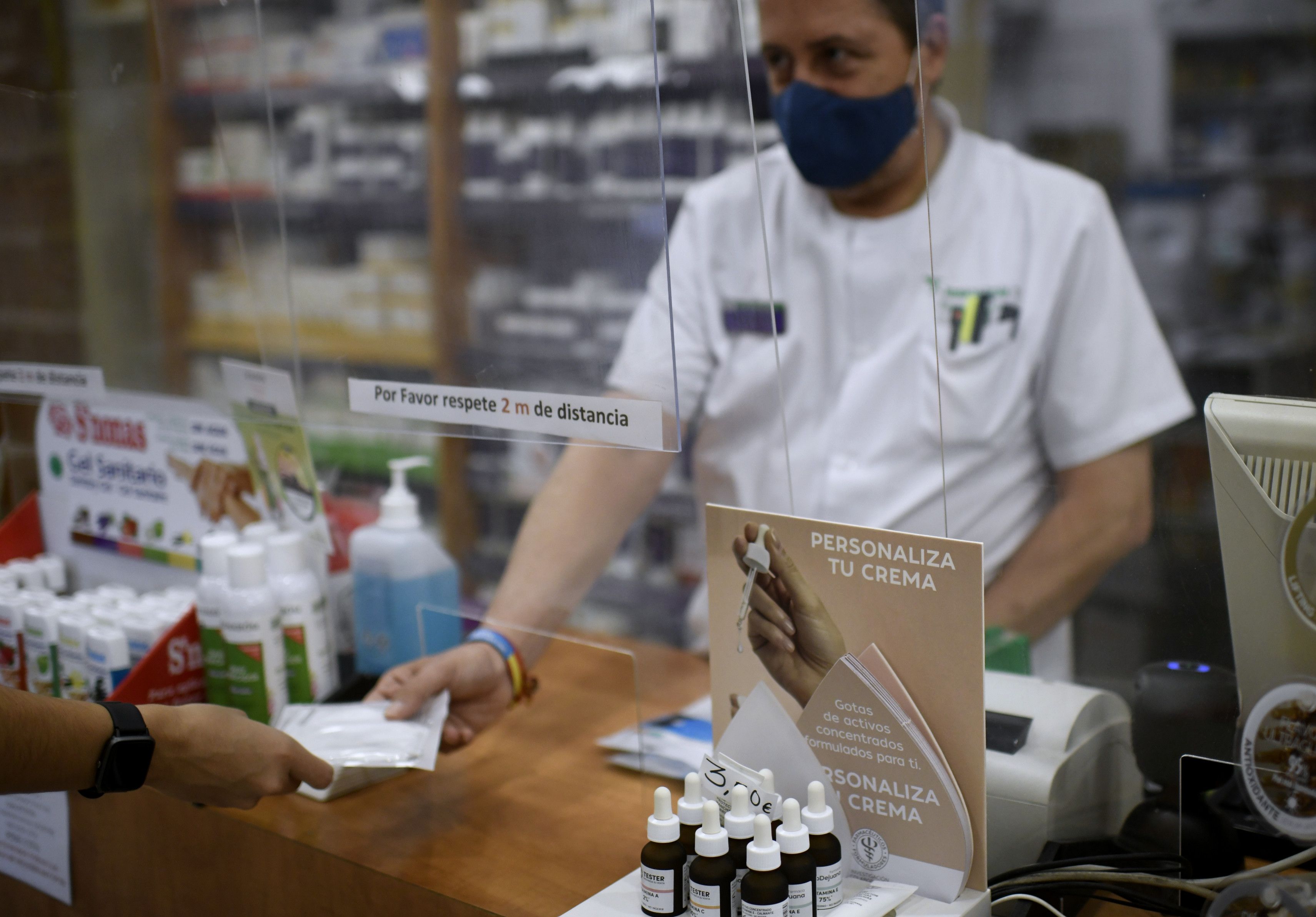 Un farmacéutico entrega a un cliente una de las mascarillas KN95 que ha recibido en su farmacia