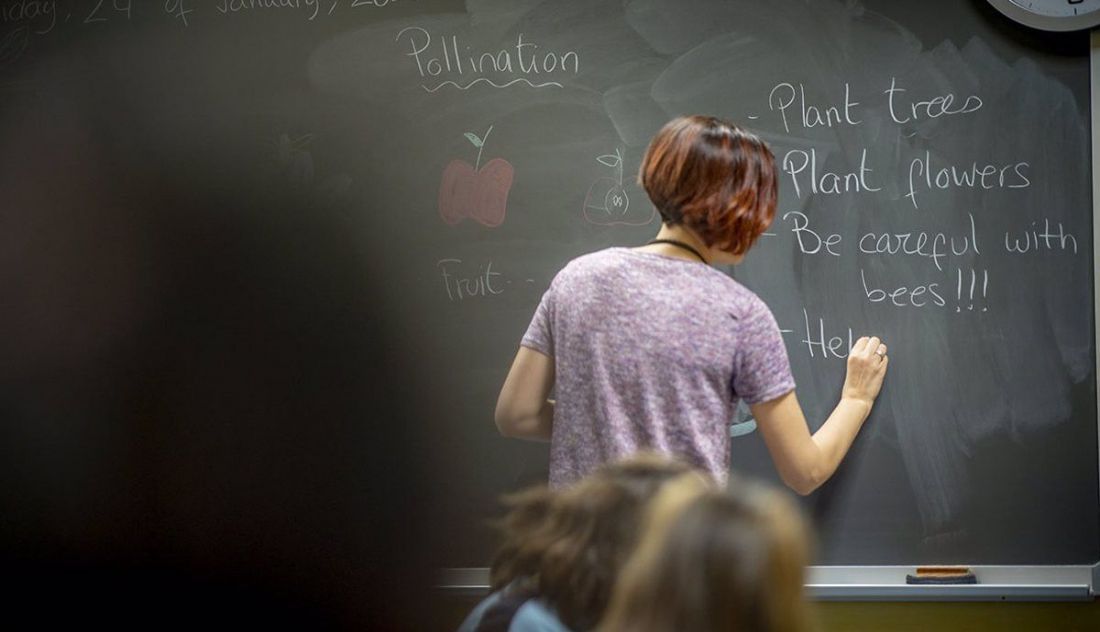 Docente escribe en la pizarra